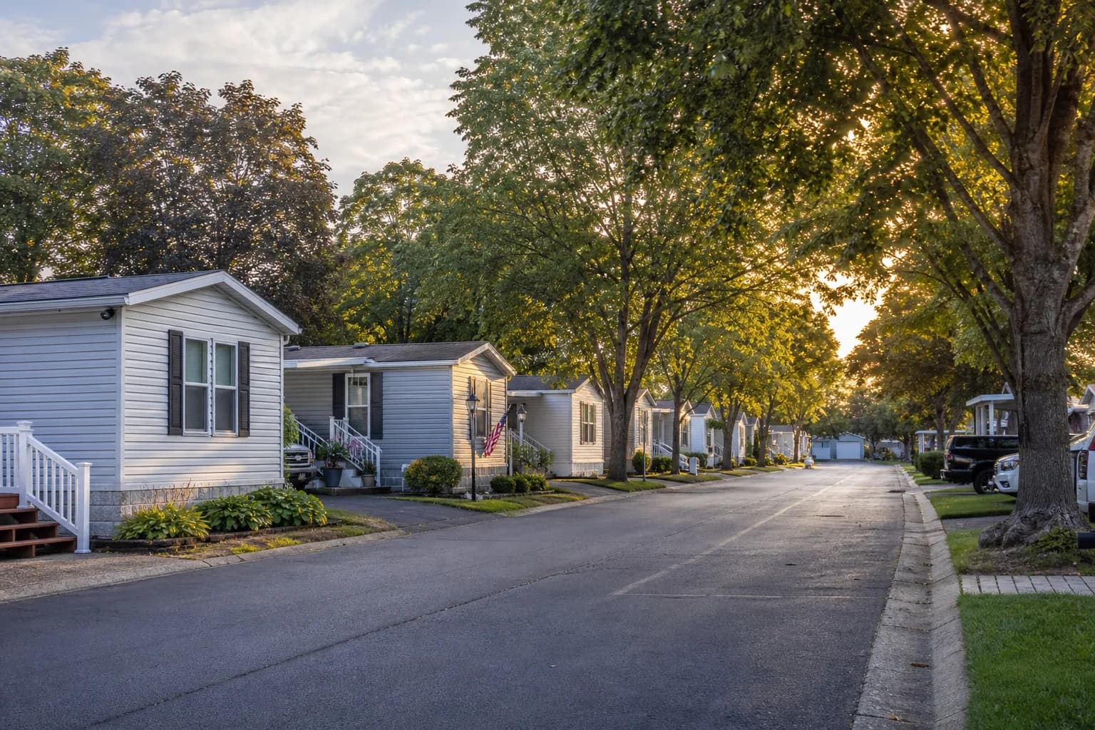 Quiet mobile home park street with mature trees at golden hour